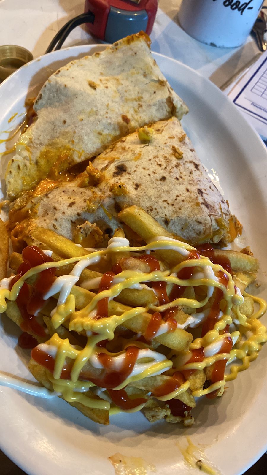 Burrito envuelto en papel aluminio junto a papas fritas y salsas